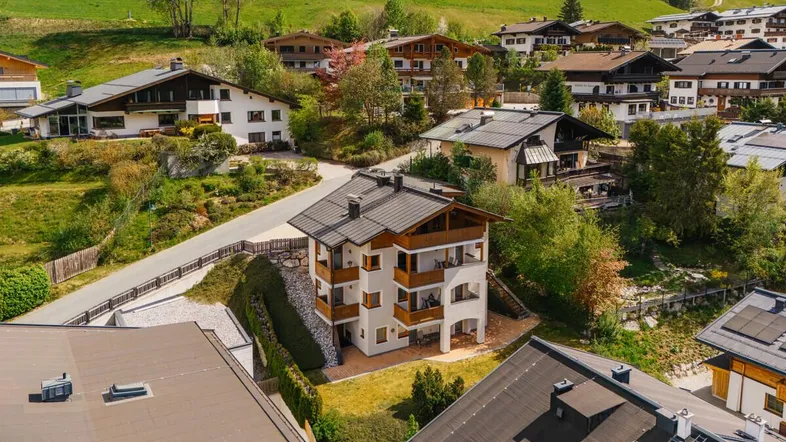 Luftaufnahme eines mehrstöckigen Gebäudes in einer bergigen Wohngegend mit traditioneller Architektur.