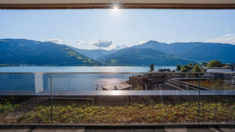 Große Terrasse mit Glasgeländer und atemberaubendem Blick auf den See und die umliegenden Berge.