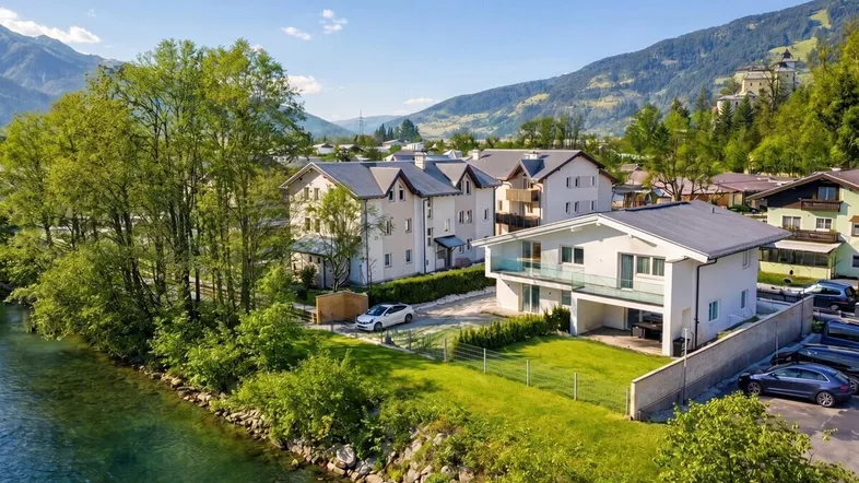 Modernes Haus am Flussufer mit Bergblick und umliegender Naturlandschaft.