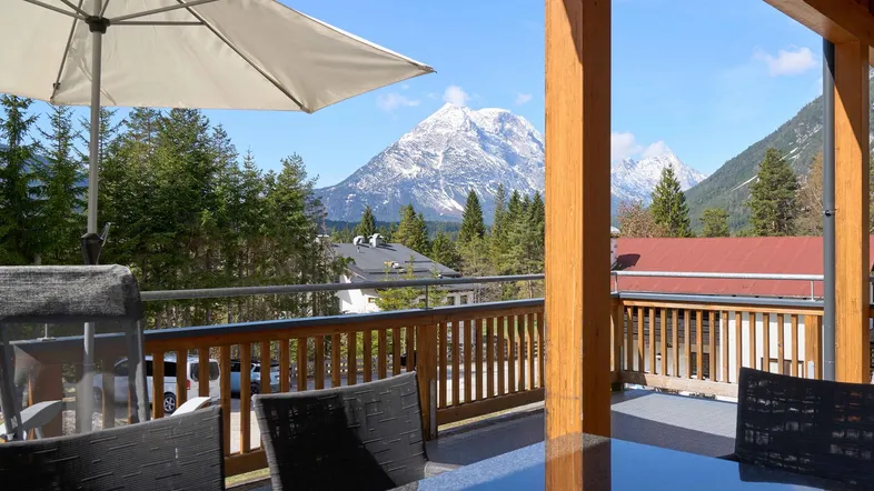 Geräumige Terrasse mit Esstisch, Sonnenschirm und beeindruckendem Bergblick auf die Alpen.