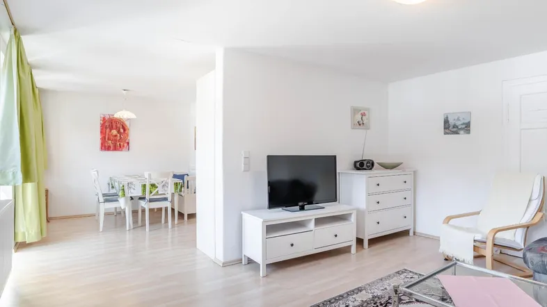 Helles Wohn- und Esszimmer mit Parkettboden, modernen Möbeln und Zugang zum Essbereich.