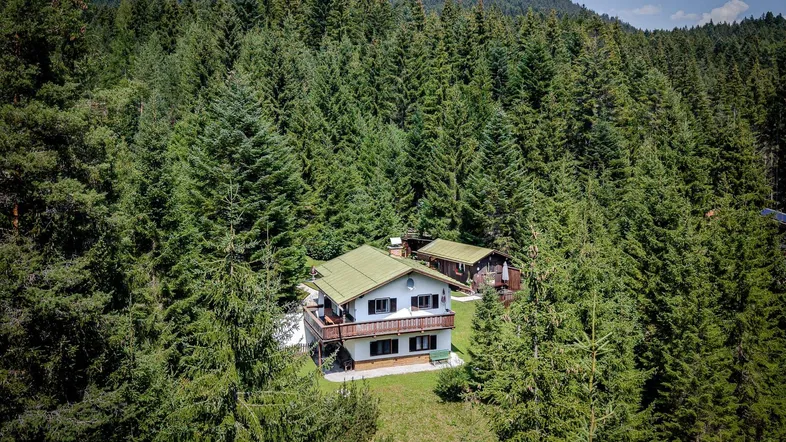 Idyllisches Haus umgeben von dichtem Wald und grüner Natur, perfekt für Ruhesuchende.