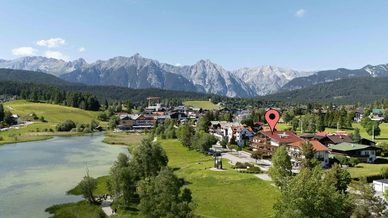 Panoramablick auf eine malerische Stadt am Seeufer mit majestätischen Bergen im Hintergrund.