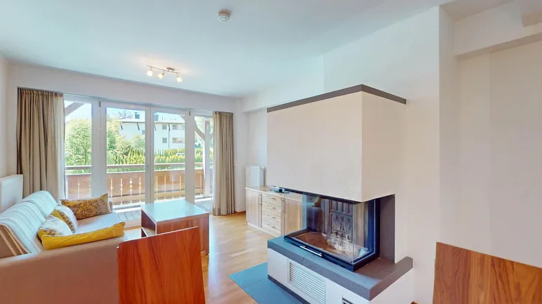 Helles Wohn- und Esszimmer mit modernem Kamin, Holzboden und Zugang zu einem Balkon.