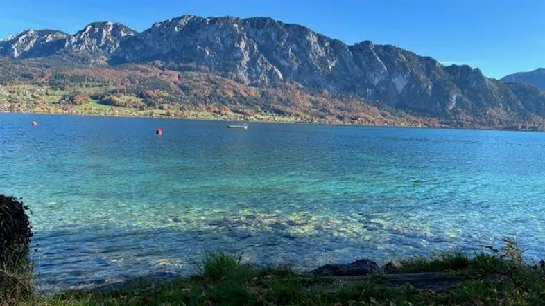 Klarer See mit majestätischem Bergpanorama unter blauem Himmel an einem sonnigen Tag.
