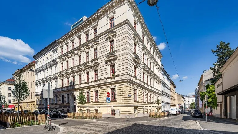 Historisches Eckgebäude mit klassischer Architektur und vielen Fenstern an einem sonnigen Tag.