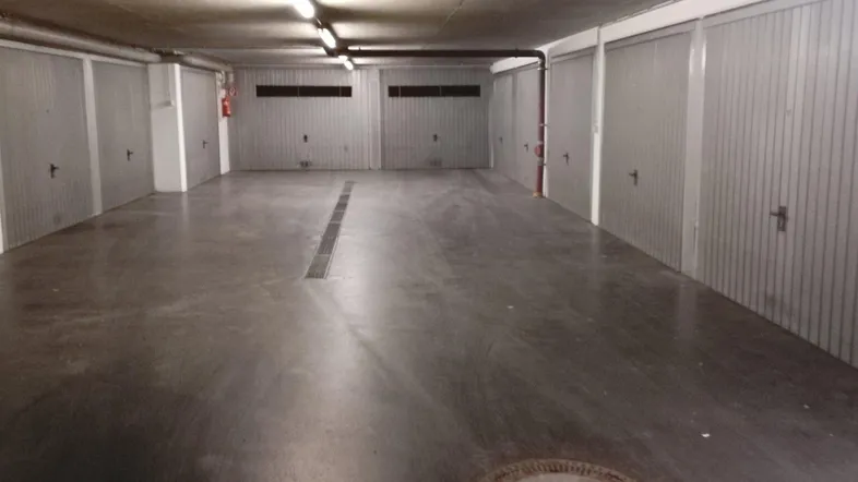 Tiefgarage mit mehreren Garagenboxen, Betonboden und Deckenbeleuchtung.