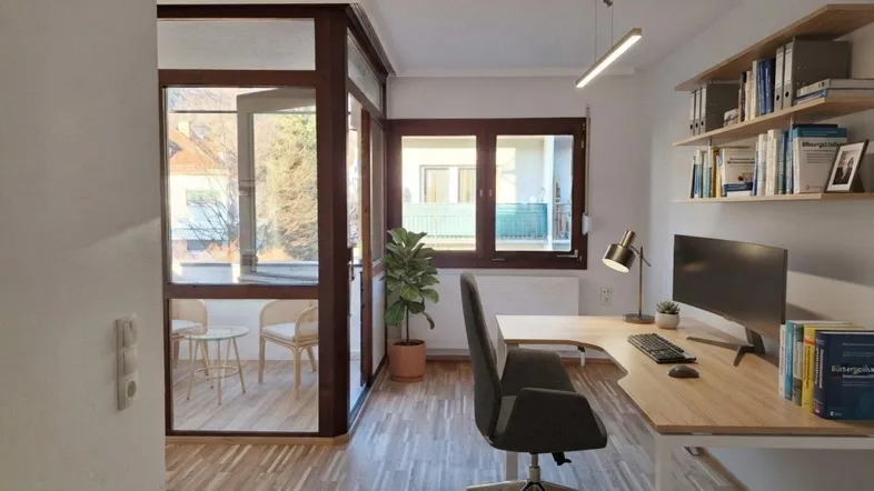 Helles Büro mit Holzfußboden, großen Fenstern und einer eleganten Glasabtrennung zu einem weiteren Bereich.
