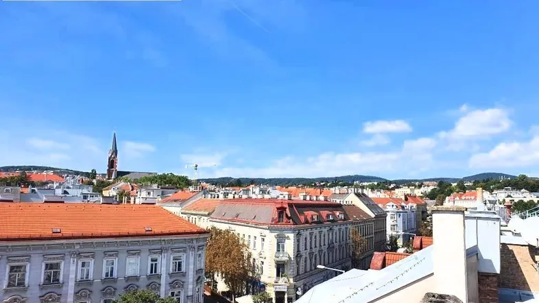Panoramablick über die Dächer der Stadt mit historischer Architektur und blauem Himmel.