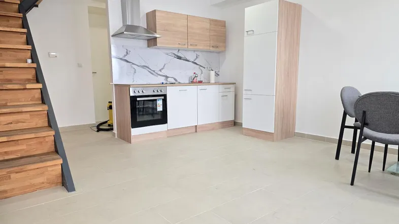 Moderne Einbauküche mit hellen Fronten, Marmoroptik-Rückwand und angrenzendem Essbereich.