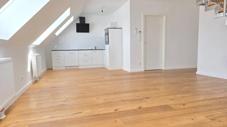 Heller offener Wohnbereich mit integrierter Küche, Holzboden und Dachfenstern.