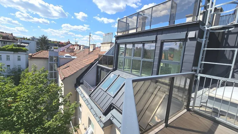 Moderne Dachgeschosswohnung mit Glasgeländer und Terrasse, bietet einen weiten Blick über die Stadt.