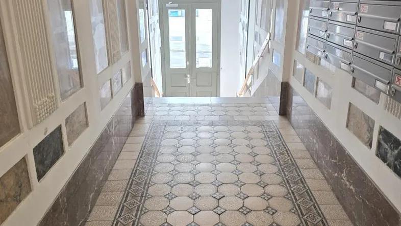 Prunkvoller Eingangsbereich eines Altbaus mit kunstvollem Mosaikboden und historischen Details.