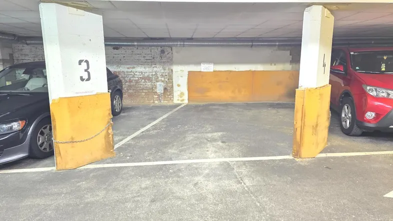 Tiefgaragenstellplatz mit ausreichend Platz zwischen den Pfeilern für ein Fahrzeug.