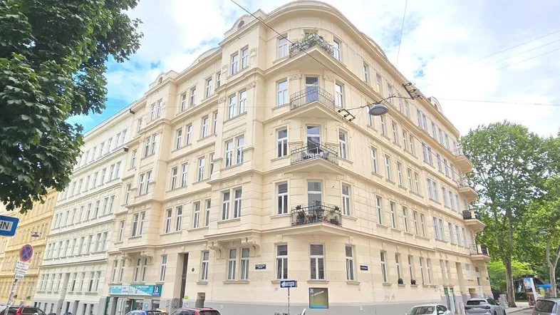 Mehrstöckiges Eckgebäude mit klassischer Architektur und vielen Fenstern in städtischer Umgebung.