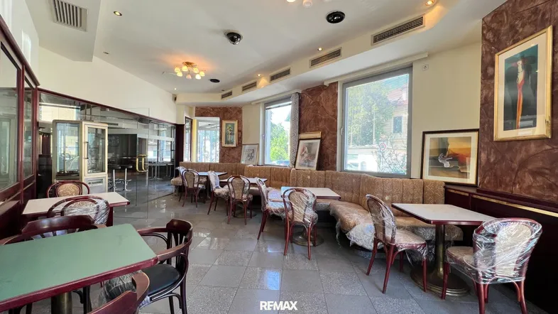 Geräumiger Gastraum mit Tischen, Stühlen und einer langen Sitzbank, ideal für ein Café oder Restaurant.