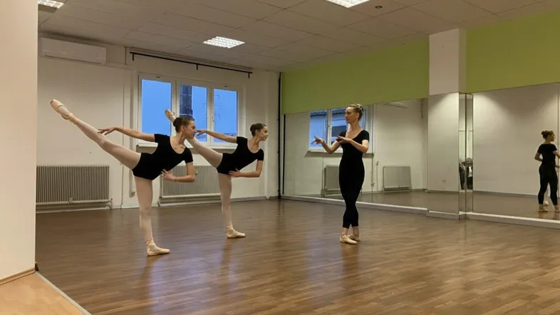 Geräumiges Tanzstudio mit Holzfußboden, großen Spiegeln und Fenstern, ideal für Ballettunterricht.