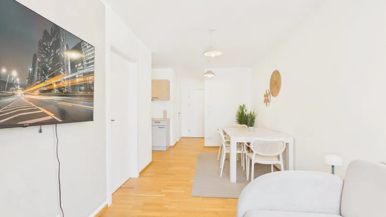 Helles Wohn- und Esszimmer mit Holzboden, modernem Sofa und Esstisch für mehrere Personen.