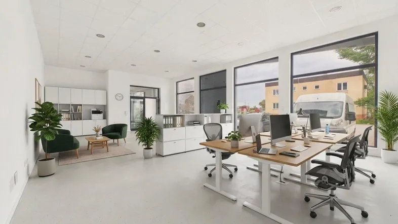 Modernes Büro mit mehreren Arbeitsplätzen, einem Loungebereich und großen Fenstern für viel Tageslicht.