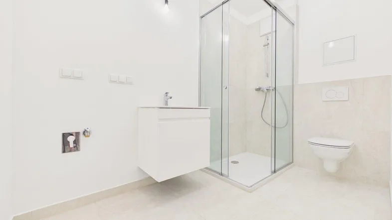Modernes Badezimmer mit Duschkabine, Waschbecken und Toilette in hellen Farbtönen.