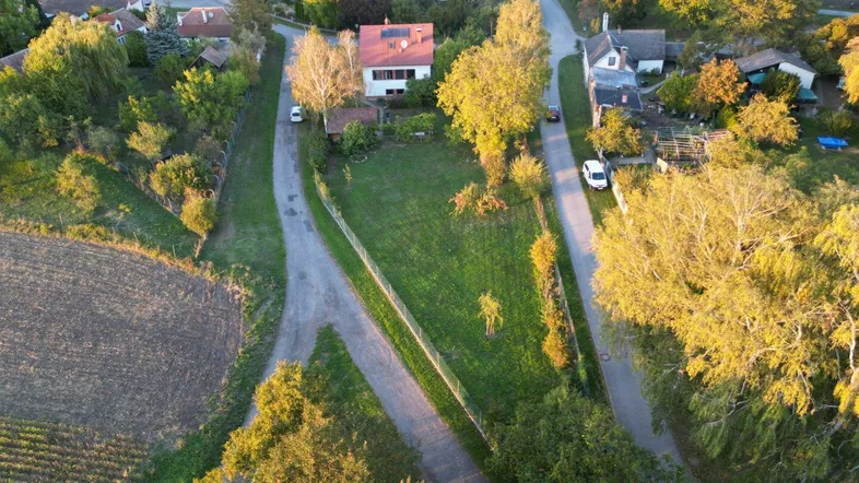 Luftaufnahme eines Einfamilienhauses mit großem Garten und ländlicher Umgebung bei Sonnenuntergang.