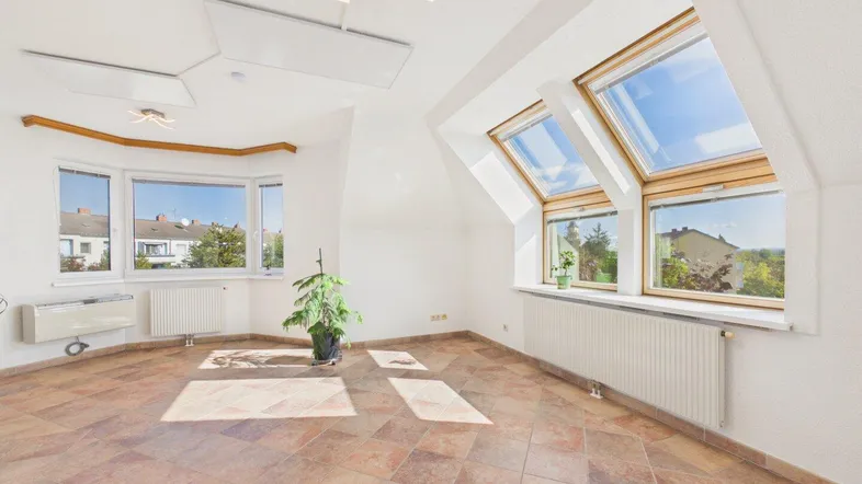 Helles und geräumiges Wohnzimmer mit Fliesenboden, Erkerfenstern und Dachfenstern, bietet viel Tageslicht.