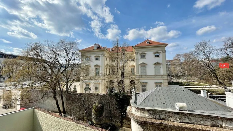 Blick auf ein historisches Gebäude mit Gartenanlage unter blauem Himmel.