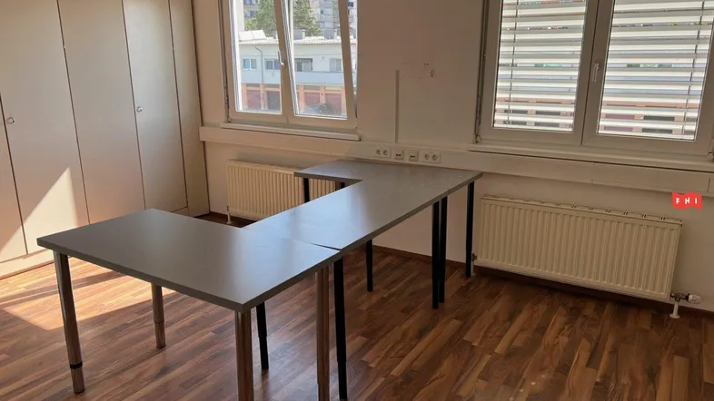 Funktionaler Büroraum mit L-förmigen Schreibtischen, Einbauschränken und Holzboden.