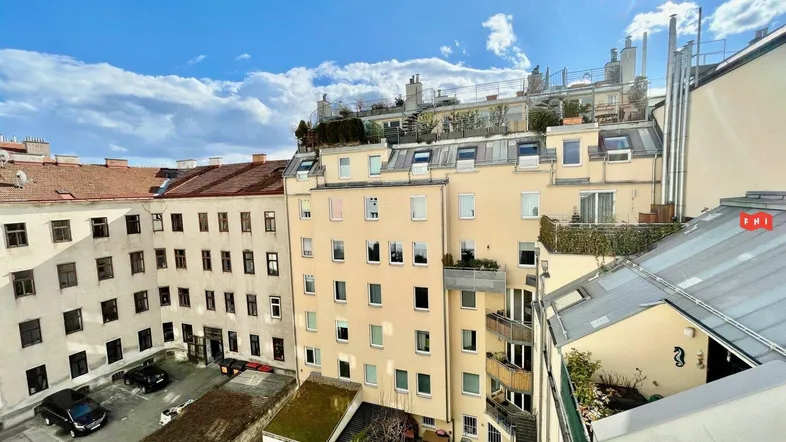 Blick auf den Innenhof und die umliegenden Gebäude mit Dachterrassen unter blauem Himmel.