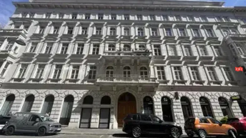 Klassische Fassade eines eleganten Mehrfamilienhauses mit vielen Fenstern und einem verzierten Balkon.