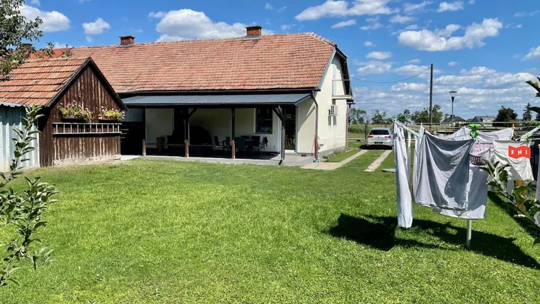 Großer grüner Garten mit Wäscheleine und Blick auf das traditionelle Wohnhaus mit überdachter Terrasse.