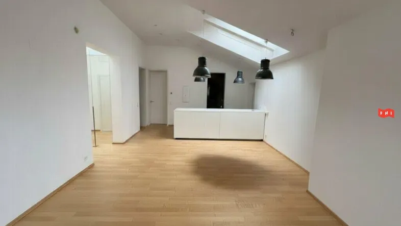 Heller, offener Wohnbereich mit Holzboden, Dachfenster und moderner Beleuchtung.