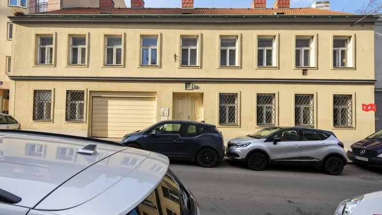 Gelbes Gebäude mit mehreren Fenstern und einer Garageneinfahrt an einer städtischen Straße.