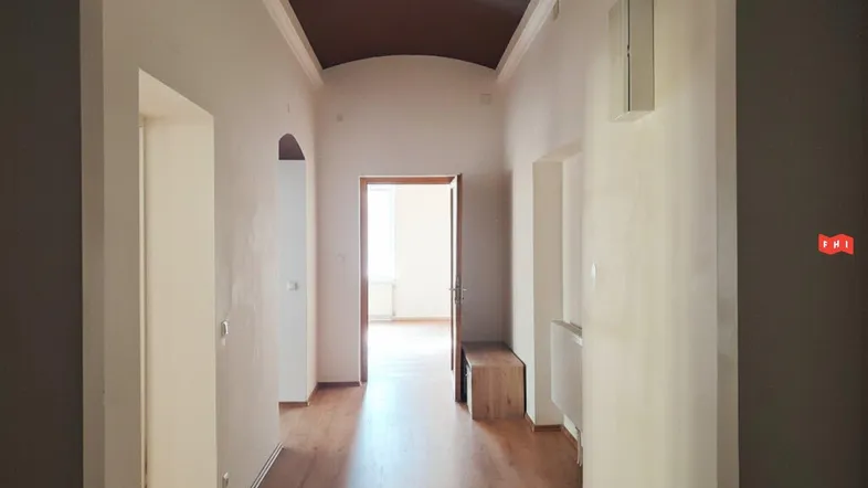 Heller Flur mit Holzboden, hohen Decken und Durchgang zu weiteren Räumen.