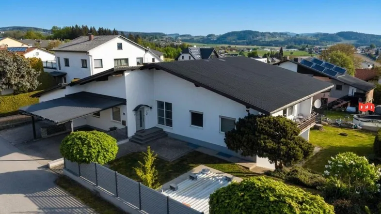 Luftaufnahme des Einfamilienhauses mit Carport, Garten und umliegender Wohnsiedlung.