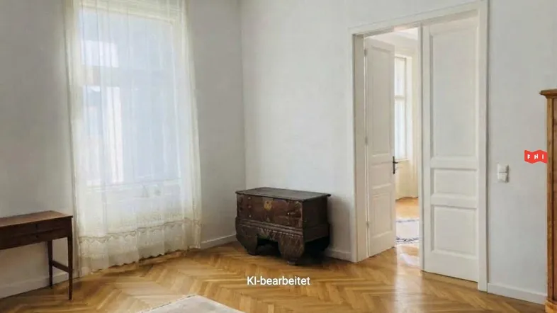 Helles Wohnzimmer mit Fischgrätparkett, hohen Fenstern und klassischer Holztruhe.