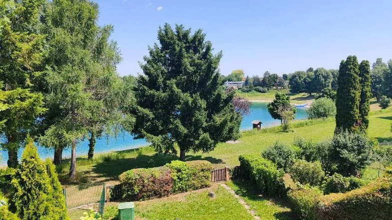 Panoramablick auf den See von einem gepflegten Garten mit üppiger Vegetation und direktem Zugang zum Wasser.