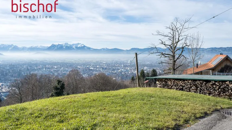 Panoramablick über das Tal mit Stadt, Bergen und einem Haus auf dem Hügel.