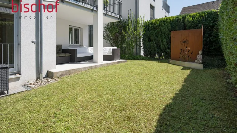 Gepflegter Gartenbereich mit Rasenfläche und einer überdachten Terrasse mit Sitzgelegenheiten.