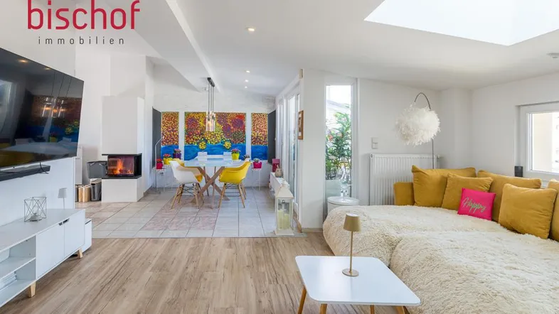 Helles, offenes Wohn- und Esszimmer mit Kamin, Holzboden und Zugang zum Balkon.