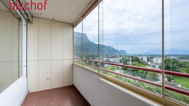 Verglaster Balkon mit Terrakotta-Fliesenboden und weitem Blick auf die Berge und die Stadt.