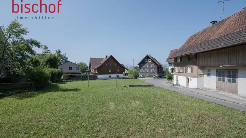 Großes grünes Grundstück mit Rasenfläche und Blick auf umliegende Häuser in ländlicher Umgebung.