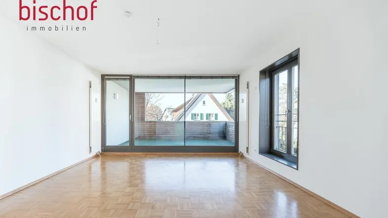 Helles, leeres Zimmer mit Parkettboden und Zugang zu einem Balkon, ideal als Wohnbereich.