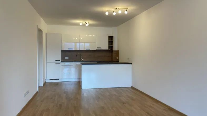 Moderne, offene Küche mit weißen Hochglanzfronten und angrenzendem Wohnbereich mit Holzfußboden.