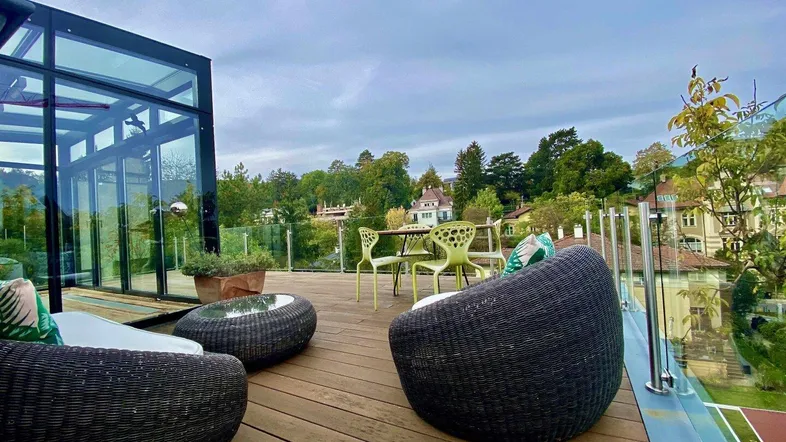 Geräumige Holzterrasse mit modernen Loungemöbeln und Blick auf die grüne Umgebung.