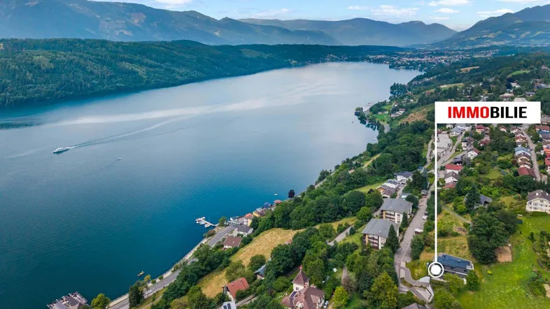 Luftaufnahme eines Sees und einer Berglandschaft mit einer markierten Immobilie am Ufer.