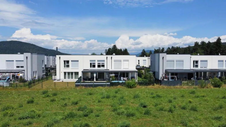 Moderne Reihenhäuser in ländlicher Umgebung mit Blick auf grüne Felder und Berge.