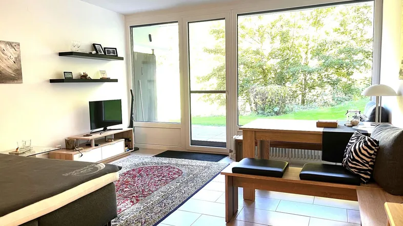 Heller Wohn- und Essbereich mit großen Fenstern, Fliesenboden und direktem Zugang zur Terrasse.