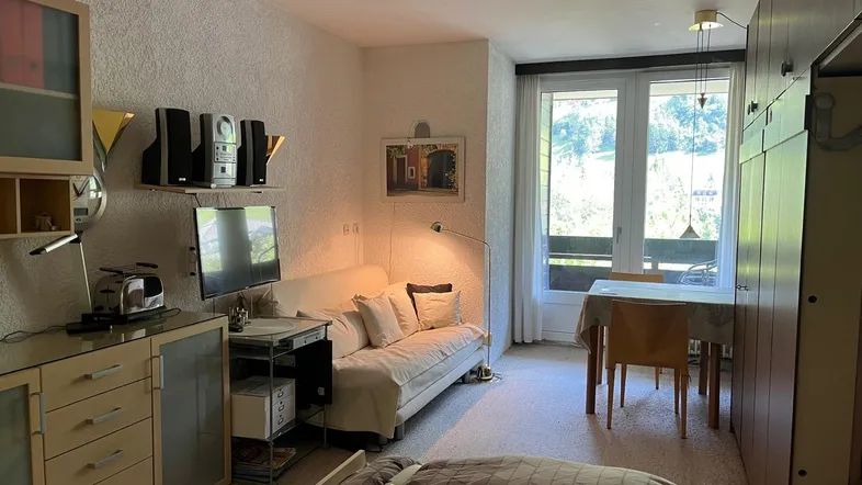 Gemütlicher Wohnbereich mit Sofa, Esstisch und Zugang zu einem Balkon mit Bergblick.