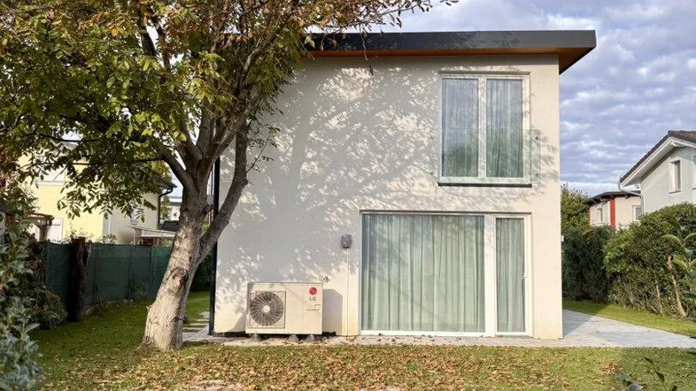 Modernes Einfamilienhaus mit weißer Fassade, großen Fenstern und einem gepflegten Garten.